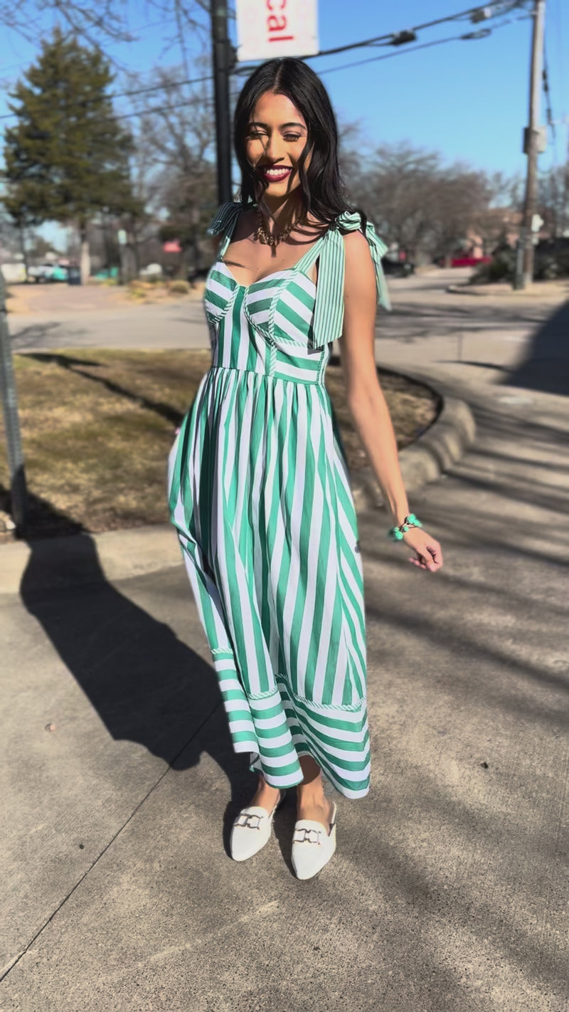 Woman wearing a green and white striped dress standing outside.