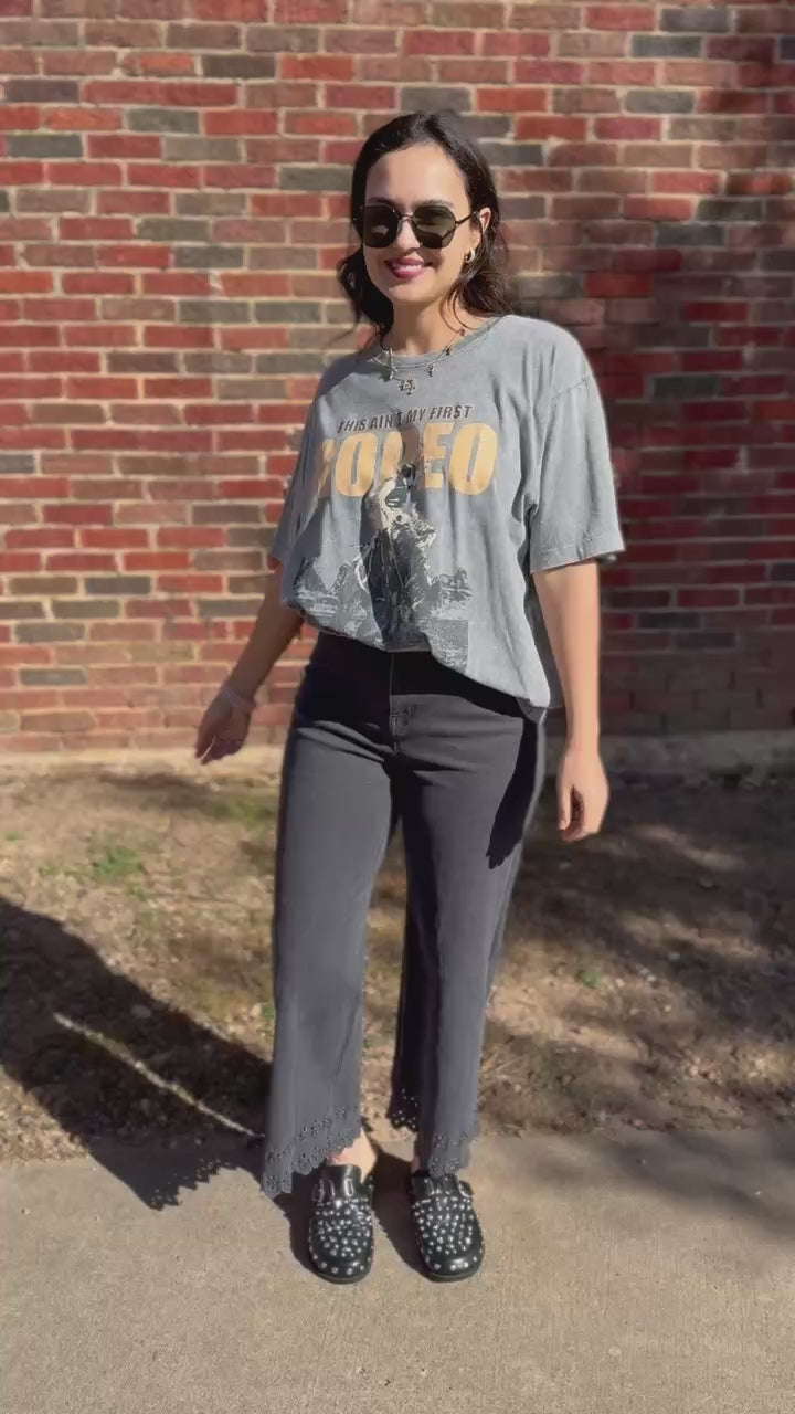 Woman wearing a graphic t-shirt and jeans standing outside.