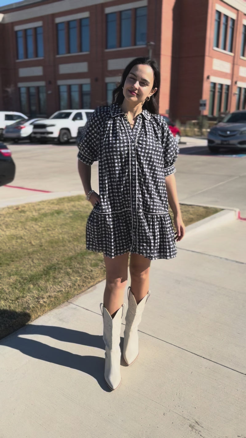 Woman wearing a blue patterned dress standing outdoors.
