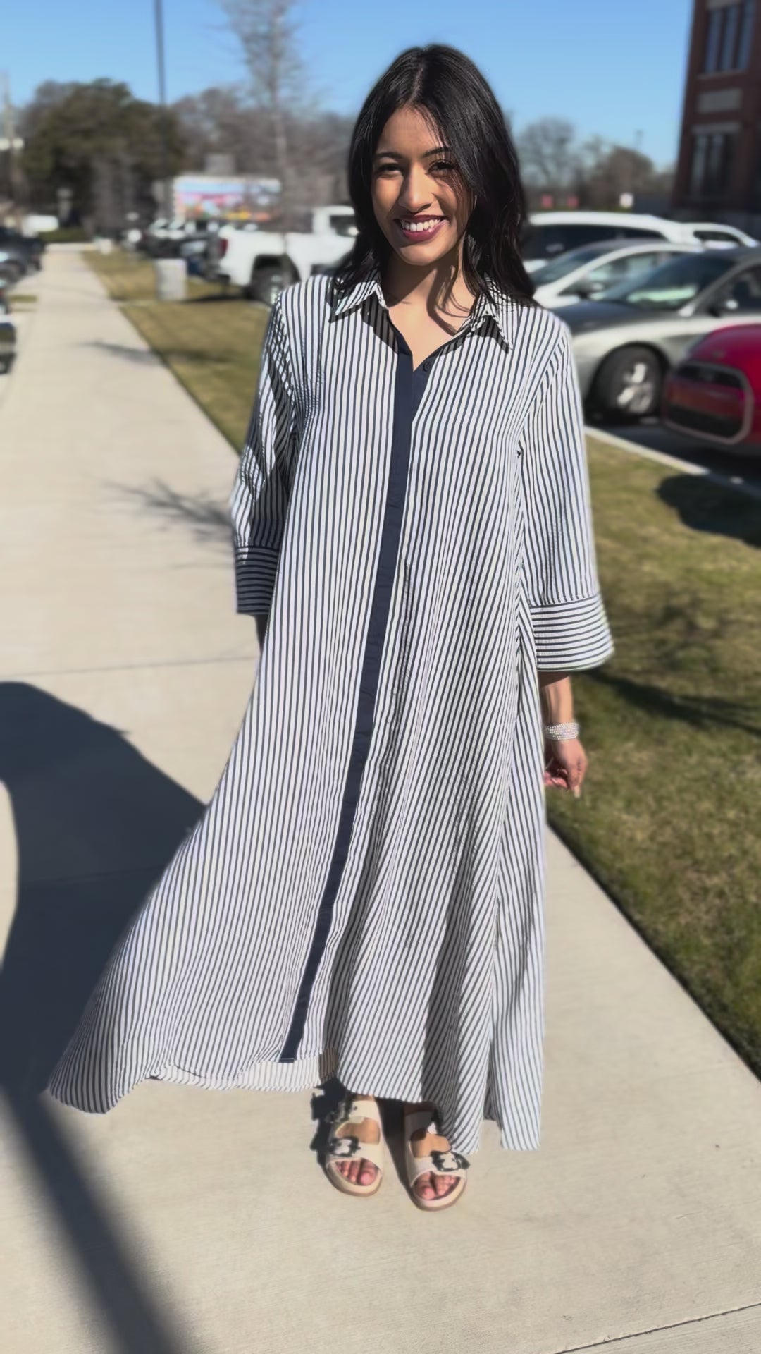 Woman wearing a long, light-colored striped dress outside.