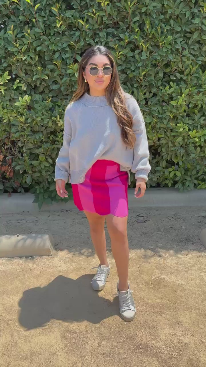 Brunette model wearing a grey top and a pink skirt in an outdoor setting. Southern House Clothing