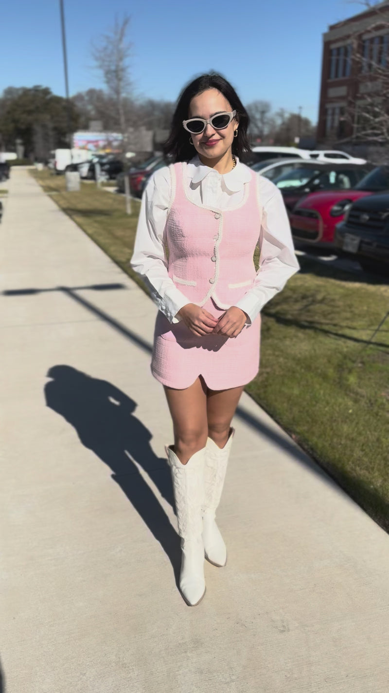 Woman wearing a light pink dress with a white shirt in an urban setting
