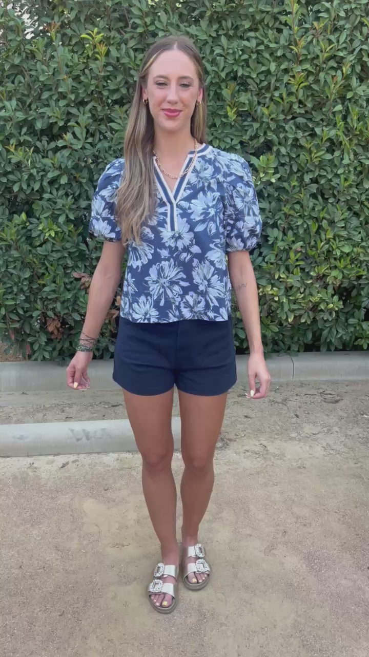 Blond model wearing navy top and shorts in an outdoor setting. Southern House Clothing.