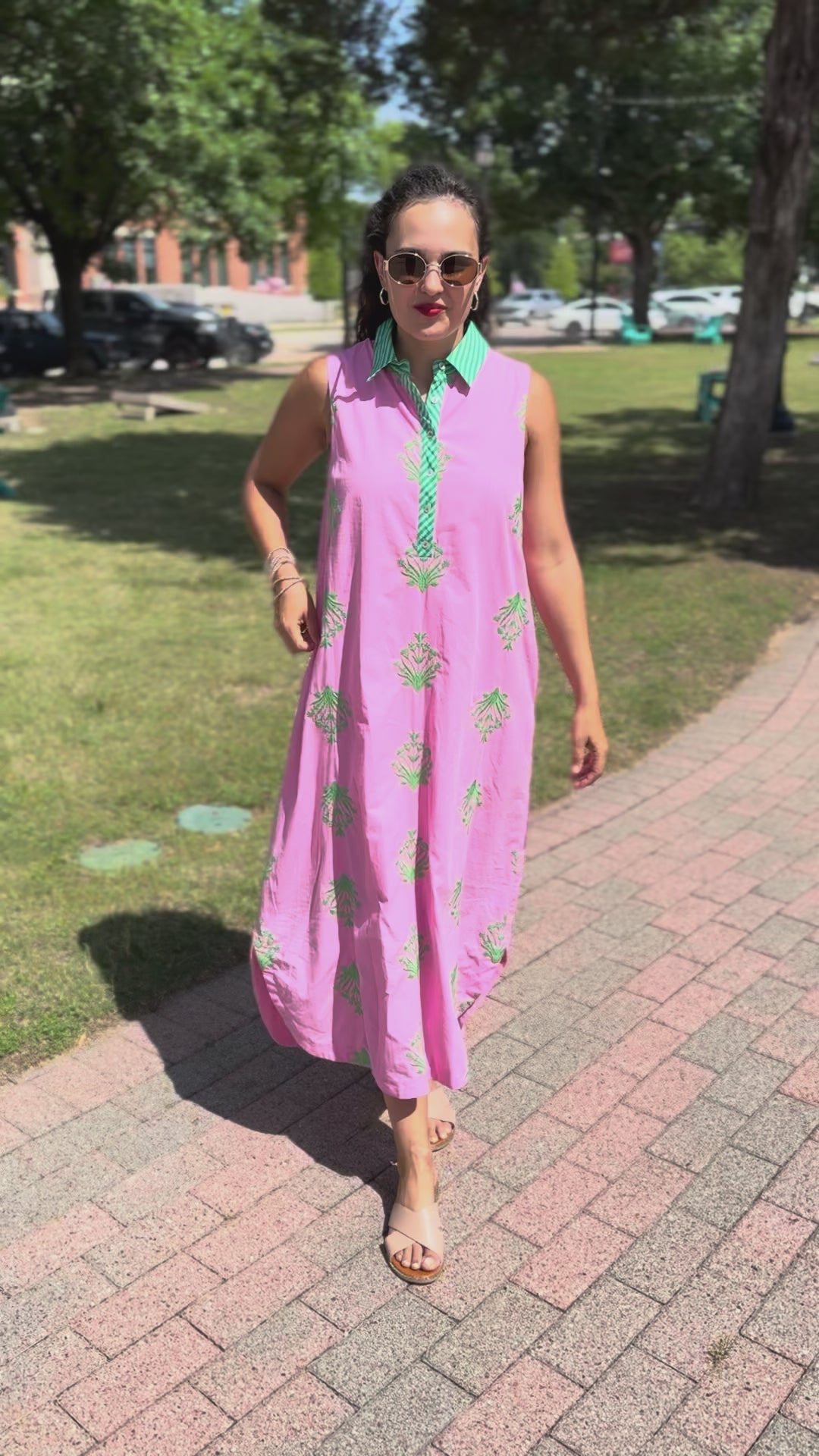 Woman in a pink dress with green patterns standing outdoors