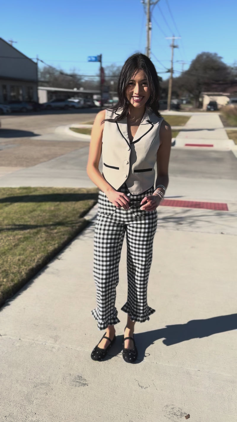 Woman wearing a beige blazer and black and white checkered pants outdoors.