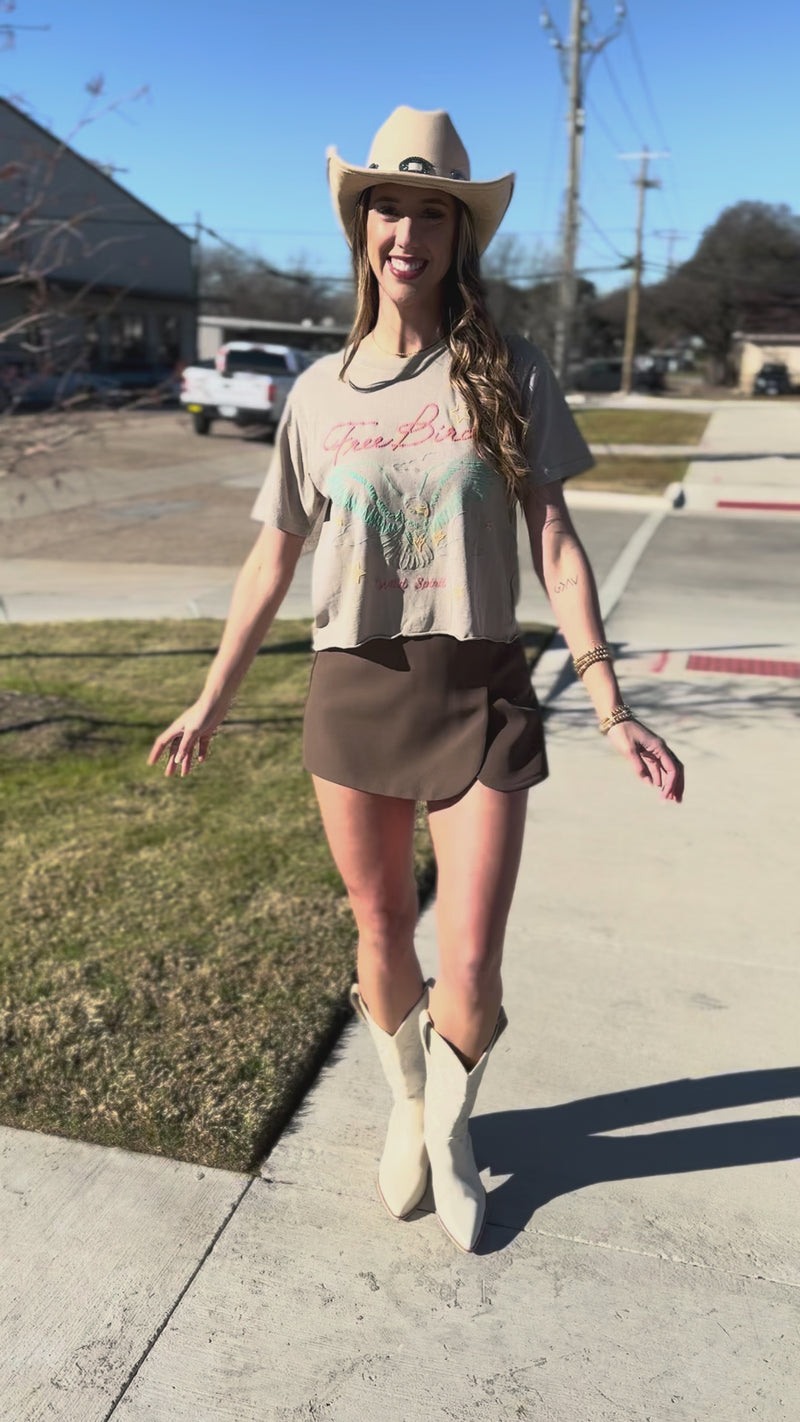 Woman wearing a 'Free Bird' t-shirt with an eagle design outdoors.