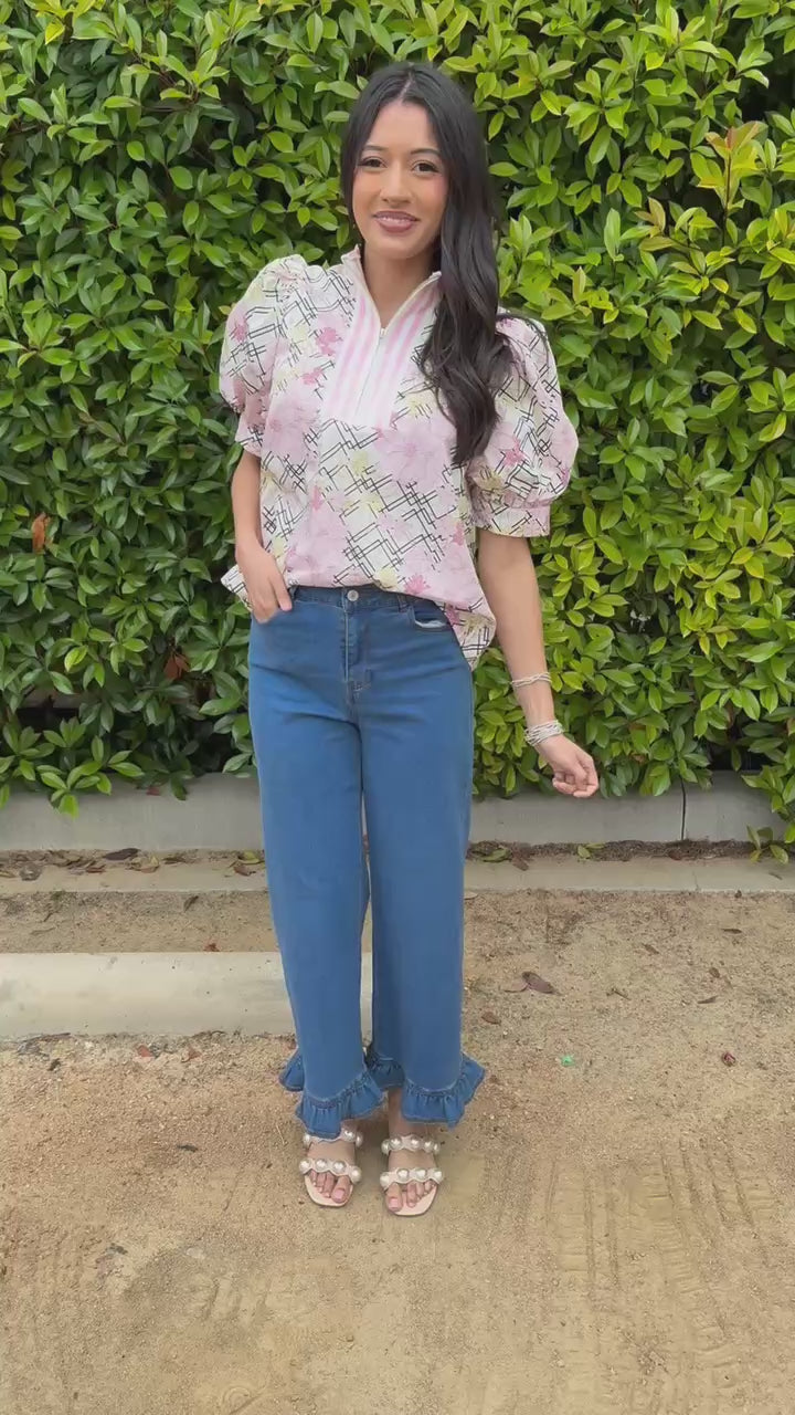 Woman wearing a floral blouse with plaid patterns and jeans outdoors.