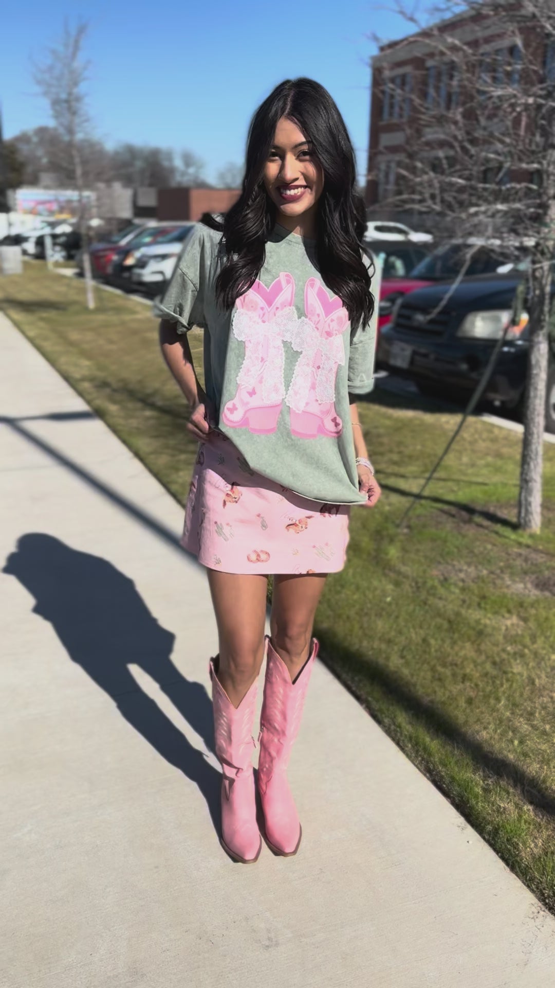 Woman wearing a green oversized shirt over a pink floral dress with a blurred background