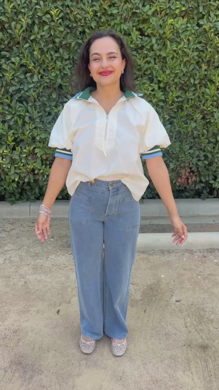 Brunette model wearing a cream top and jeans in an outdoor setting. Southern House Clothing