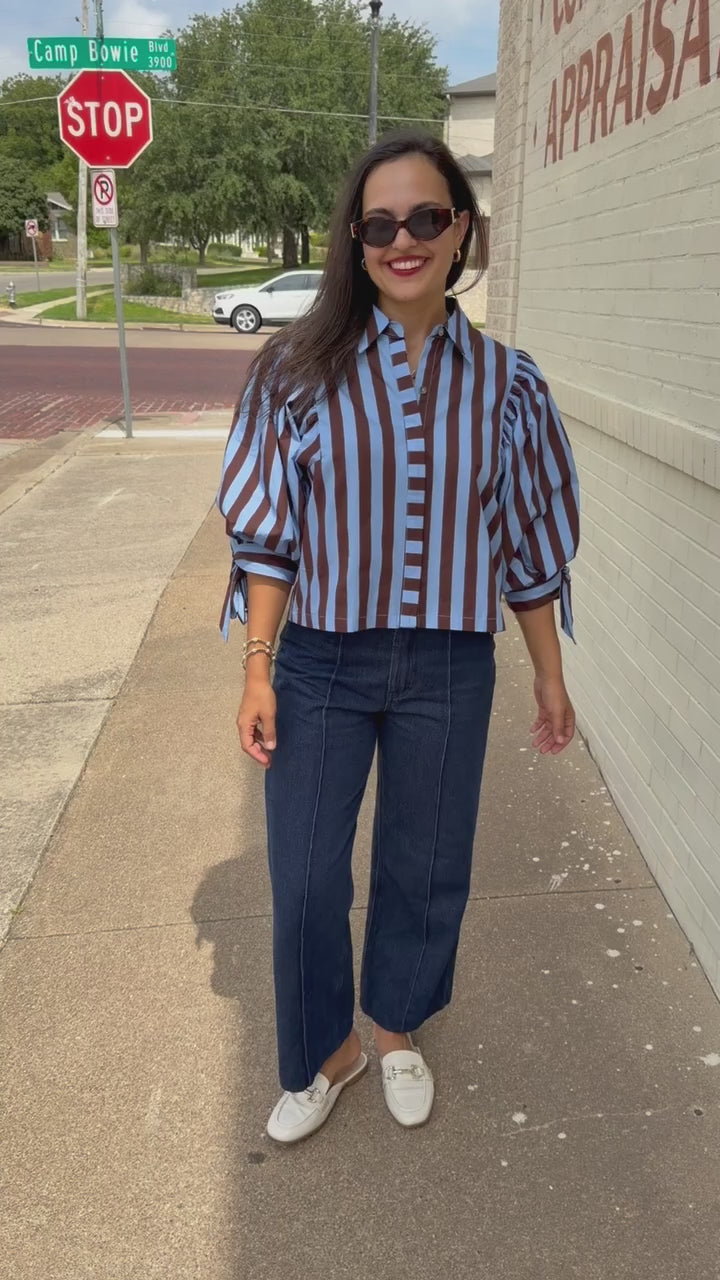Brunette model wearing a 3/4 sleeve brown and blue blouse with denim jeans outside. Southern House Clothing.