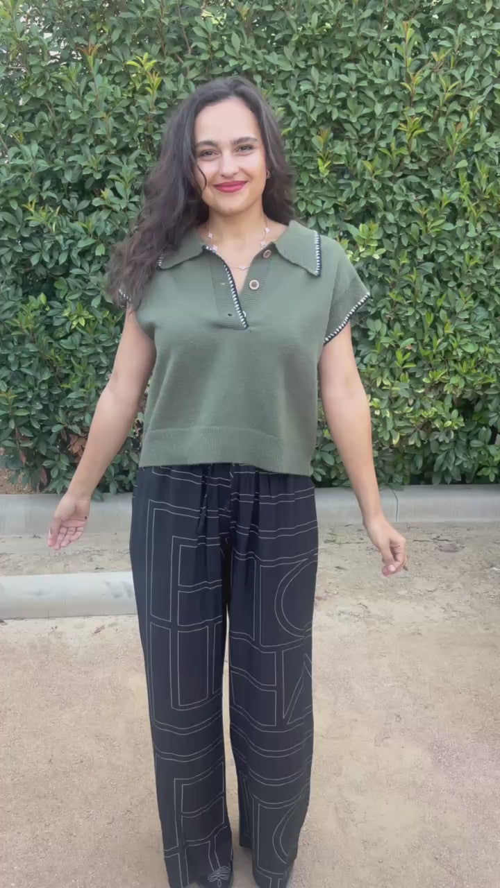 Brunette model wearing a green top and black pants in an outdoor setting. Southern House Clothing 