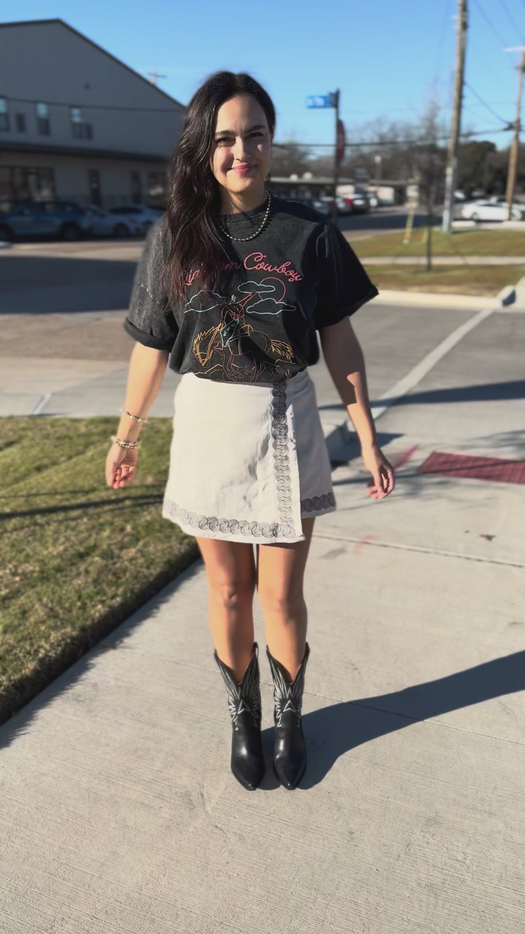 Woman wearing a graphic t-shirt with text and graphics outdoors.