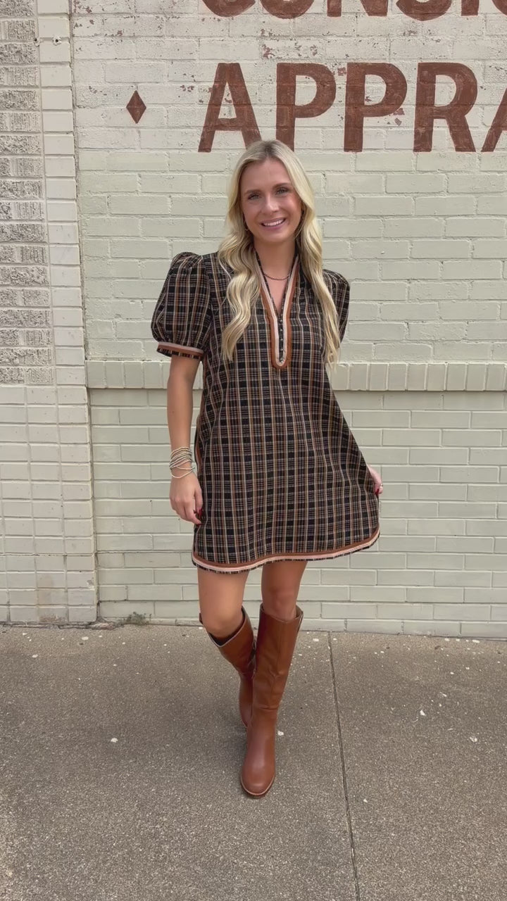 Blonde model standing outside wearing a black multi colored dress with tan boots.
Southern House Clothing