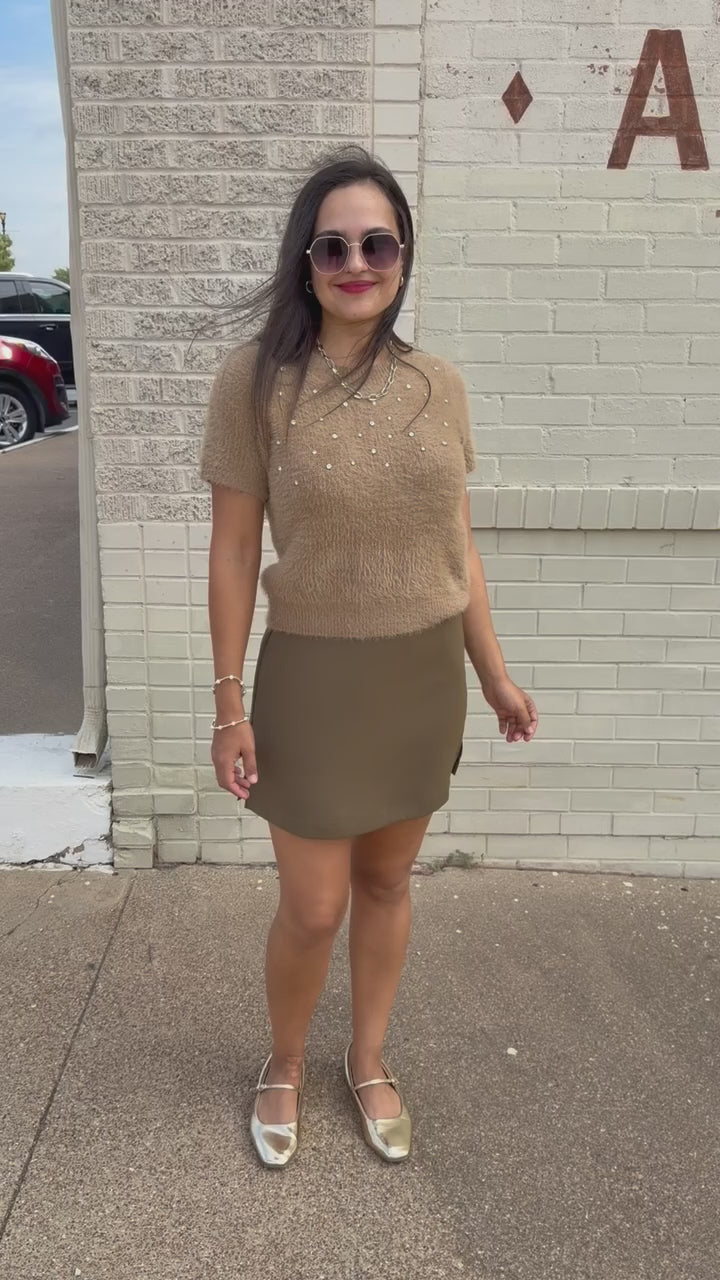 Model wearing the Liora Pearl Knit Top in Mocha with pearl-inspired embellishments and fuzzy knit texture, paired with the Winsford Mini Skort in Olive. Southern House Clothing