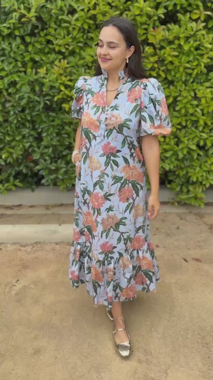 Woman wearing a floral dress in an outdoor setting.