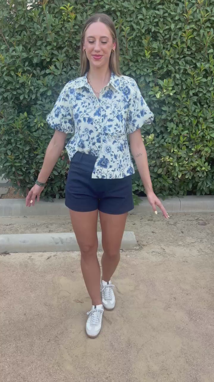 Blond model wearing a blue floral top in an outdoor setting. Southern House Clothing 