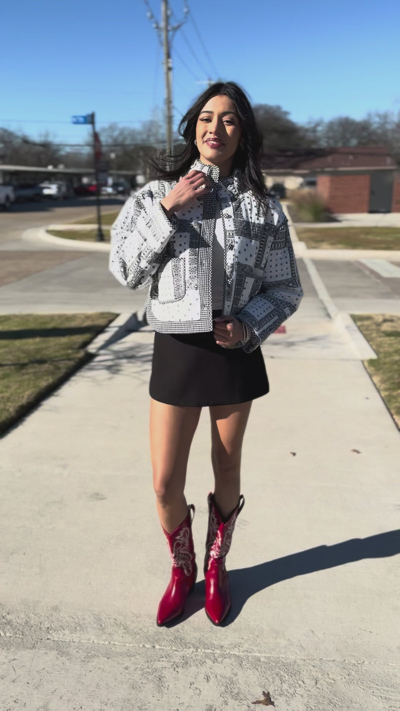Woman wearing a patterned jacket and black skirt outdoors.