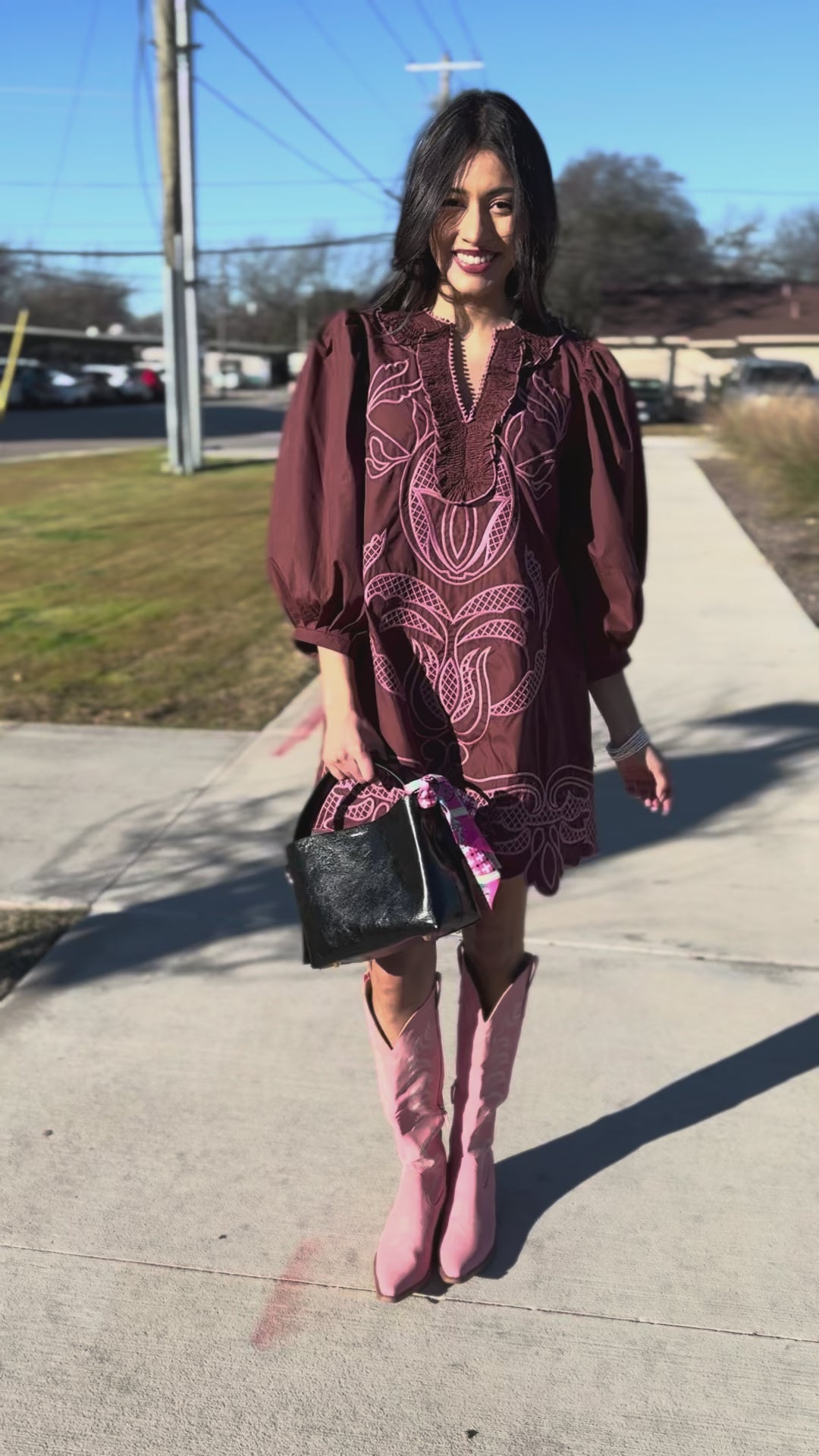 Woman in a burgundy dress with white embroidery and beige boots 