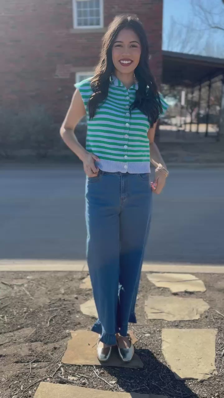 Woman wearing a green and white striped shirt and blue jeans outdoors.
