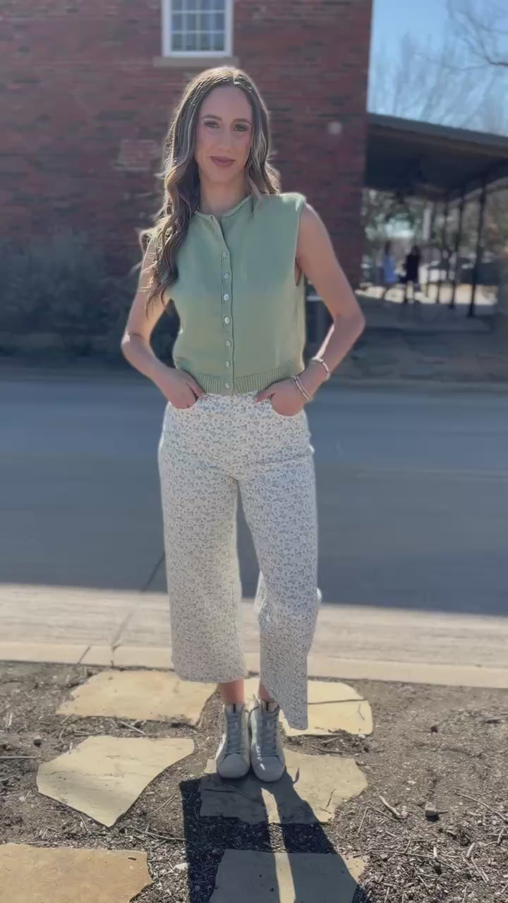 Woman wearing a green checkered shirt and beige pants outside.