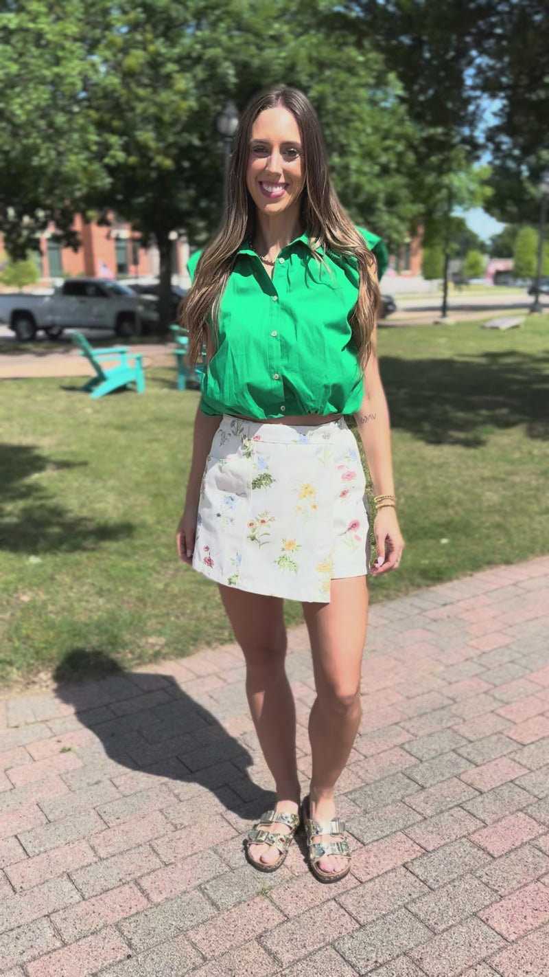 Woman wearing a green blouse with floral shorts outdoors