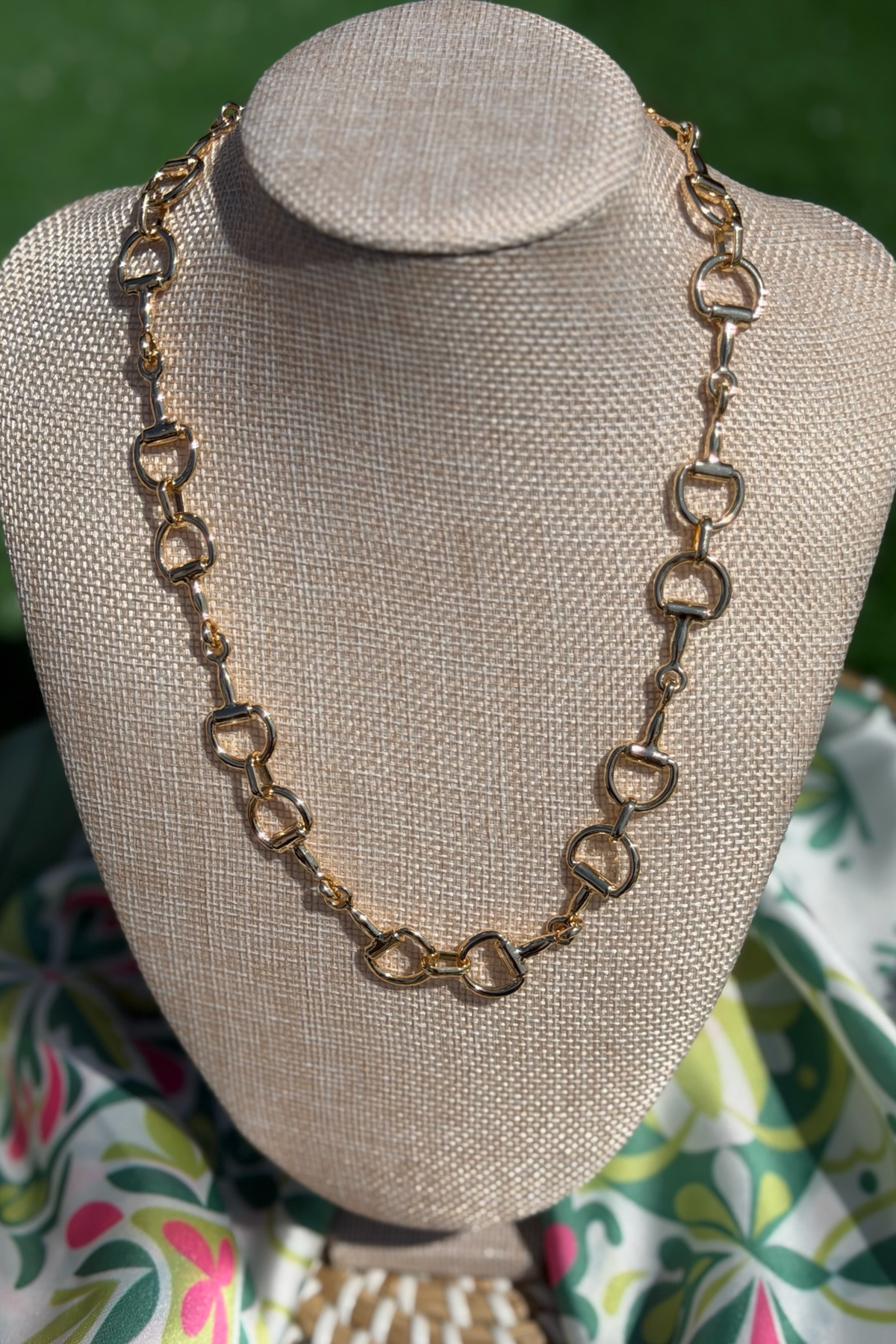 Gold necklace on a mannequin bust with a patterned fabric background