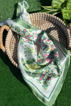 Green patterned scarf draped over a woven basket on a green surface