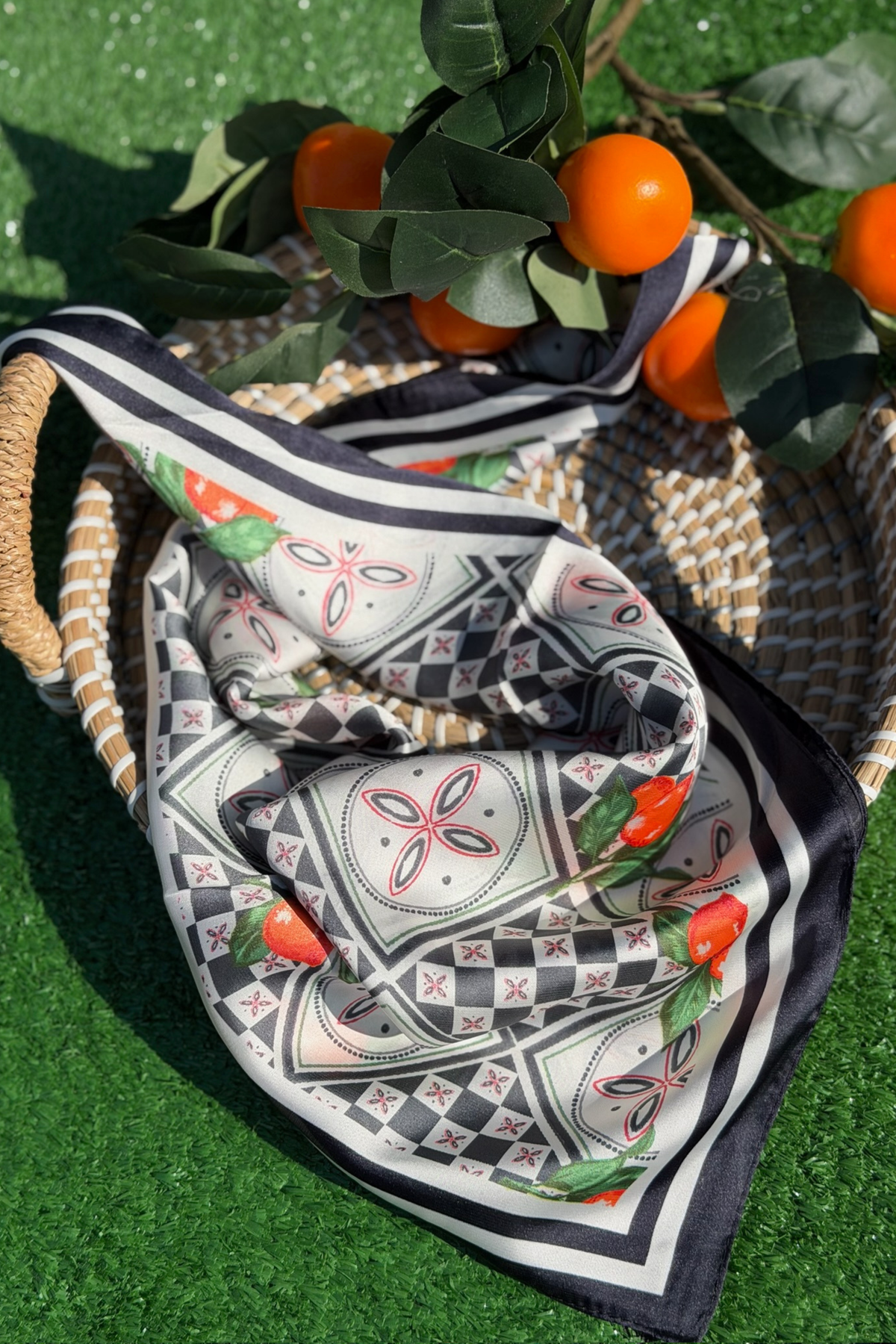 Decorative scarf with fruit pattern on a woven basket with oranges and leaves.