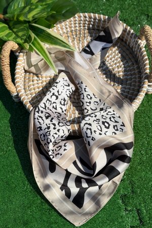 Patterned scarf draped over a woven basket on a green surface