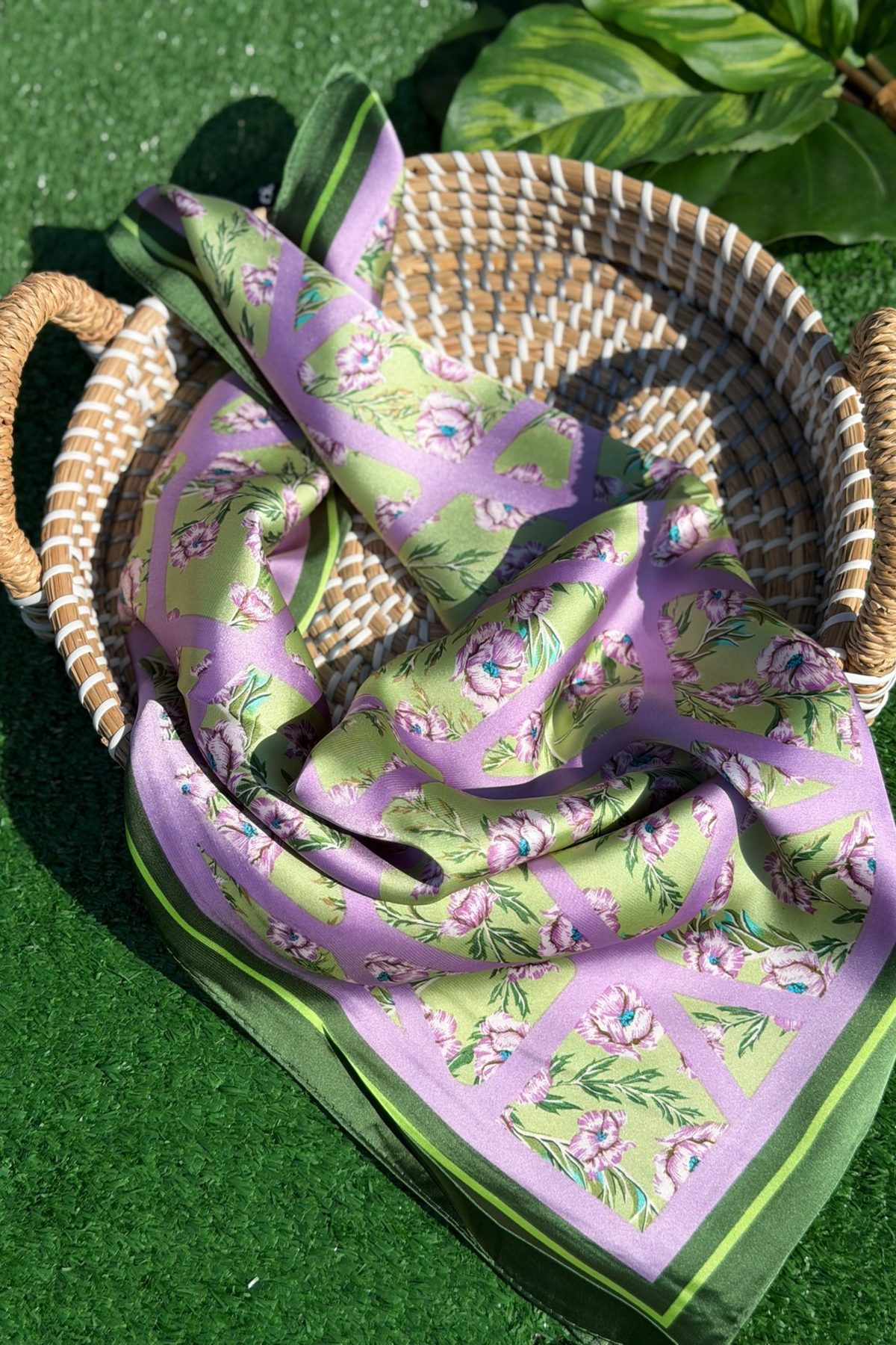 Floral-patterned fabric draped over a woven basket on grass