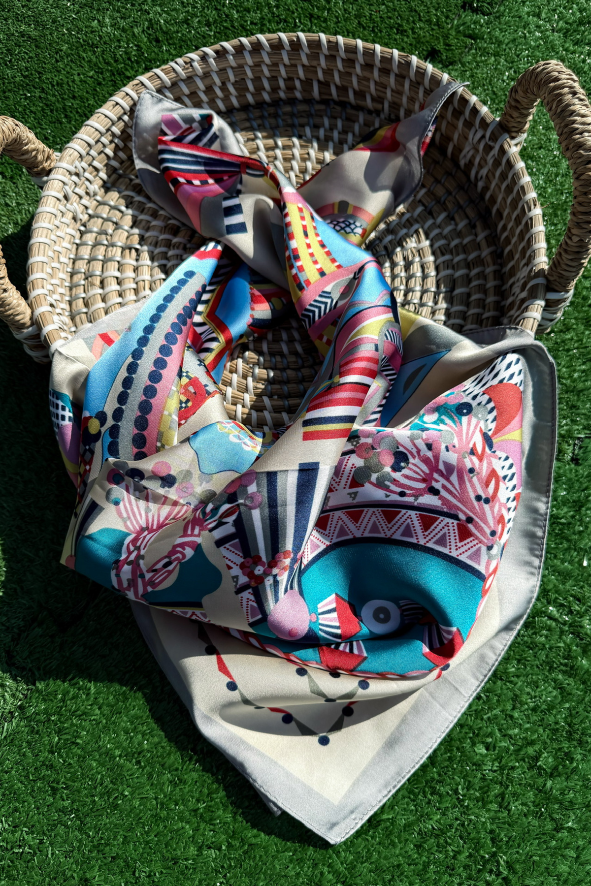 Colorful patterned fabric draped over a woven basket on grass